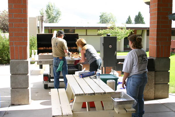 Dennis and Allison LaTulip work the smoker while Michelle Mandera watches
