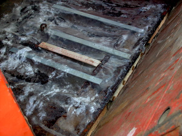 A couple pieces of steel for added support, placed over ridges in the floor, held down with resin. 1st layer of fiberglass. piec